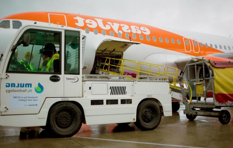 Baggage tractor and luggage cart in front of easyJet aeroplane.